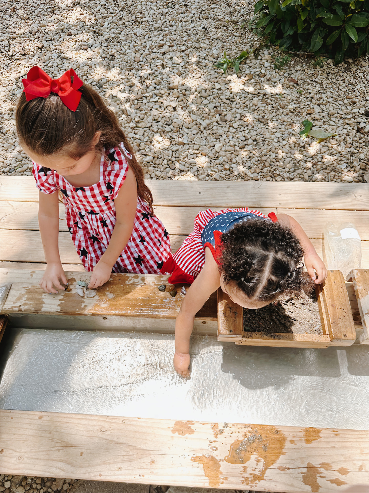 Two girls sifting for gems at the mining sluice